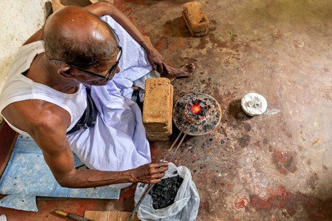 From above you can see an old man working with fire and bricks in a workshop, a man burning