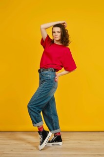 A model poses confidently in a red shirt and baggy jeans, enhancing her stylish outfit with black