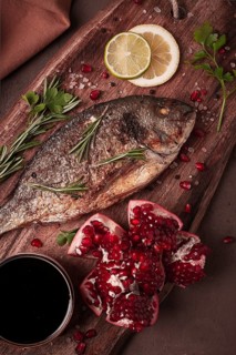 Fried dorado fish, with spices and herbs, on a wooden board, pomegranate sauce, close-up, no people