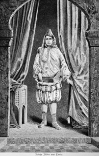 Rich Jewish woman from Tunis stands under a round arch, living room, oriental clothing, bloomers,
