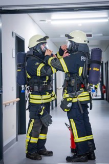 Two firefighters in full equipment communicate and prepare for deployment, fire brigade exercise on