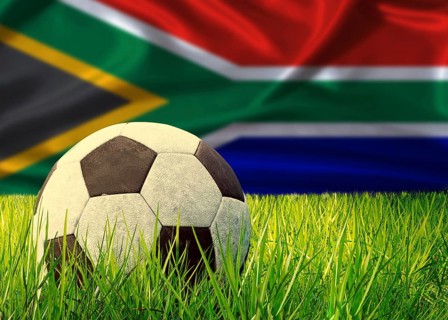 Soccer ball on the grass with South Africa flag in the background. Soccer ball on pitch against