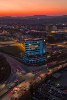 An illuminated high-rise building in the city at dusk with an orange sky, Porsche, Bietigheim,