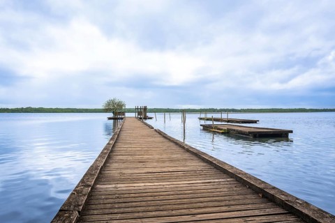 Lake azur in landes, france, offering a tranquil natural escape with a long wooden pier extending