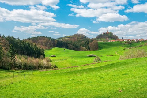 View of hilly landscape with the village of Seitenroda, the Leuchtenburg, green meadows and forests
