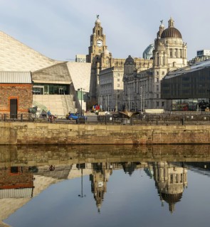 The Three Graces iconic waterfront landmark buildings reflected in water, Canning Dock, Liverpool,