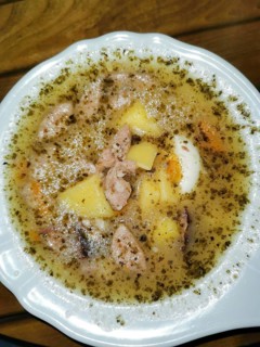 Home-made Polish zurek soup served with potatoes and meat in a white plate, Poland