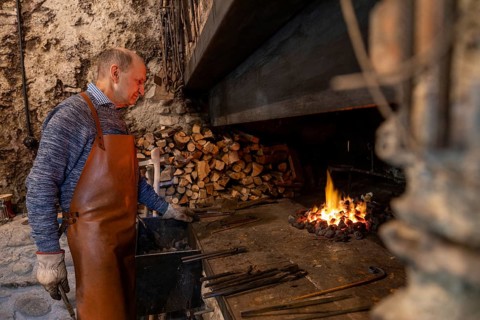 An elderly blacksmith works diligently in his Salzburg workshop, skillfully preserving