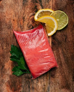Chum salmon, cold smoked, on a wooden board, with lemon and parsley, top view, close-up, no people