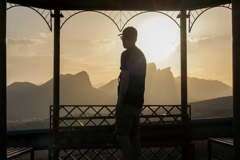 Back view of an unrecognizable man standing on a gazebo as he watches the beautiful sunrise over