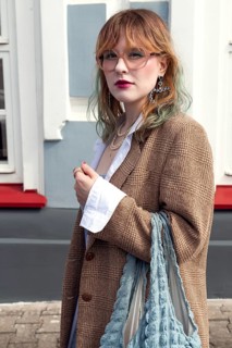 A fashionable woman with her hair dyed in vibrant colors stands confidently outdoors She is wearing