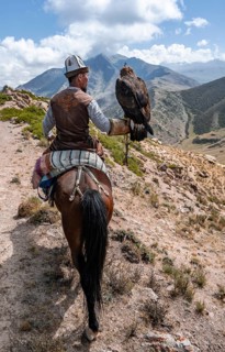 Traditional Kyrgyz eagle hunter in the mountains hunting on horseback, near Kysyl-Suu, Issyk Kul,