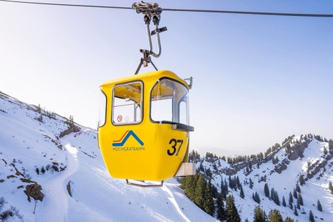 Yellow cable car floats over snowy mountainside under clear sky, Hochgrat Mountains, Allgäu Alps,