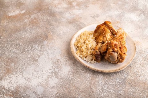 Fried Turkey Wing with spices and rice on brown concrete background. side view, copy space