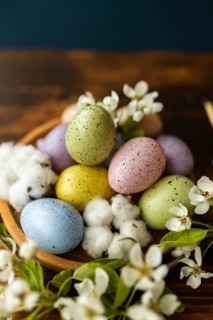 A festive arrangement of speckled Easter eggs in soft pastel hues, nestling among delicate white