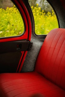 A glimpse into the interior of a classic Citroen two horses car with bright red seats and sleek