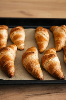 Golden brown homemade croissants fresh from the oven, displayed on a baking tray. These flaky