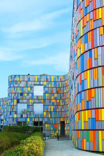 **Vibrant multicolor facade of a curved contemporary building under a clear sky, showcasing a