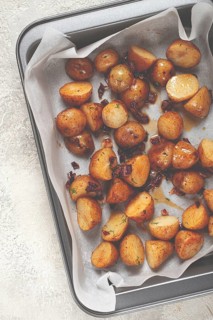 Freshly roasted potatoes golden brown and crispy, seasoned with herbs, resting on parchment paper