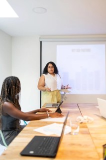 A professional female engaging in a presentation within a modern, diverse coworking space.