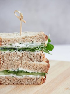 Close up view of cucumber and green spinach sandwich, cut in half and stacked, topped with a bamboo