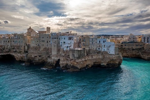 Gorgeous view of Polignano a Mare's stone and whitewashed buildings perched on rocky cliffs above