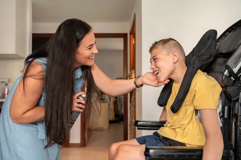 A mother shares a joyful moment with her son with cerebral palsy, interacting affectionately in a