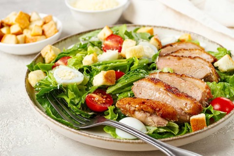 Caesar salad, with duck breast, on a light plate, on a light background, homemade, no people