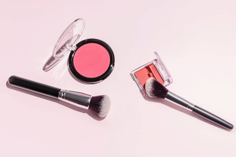 A flat lay image showcasing makeup essentials on a pastel pink background Included are vibrant