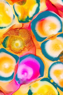 An abstract image featuring vibrant swirls of ink in a variety of colors including pink, yellow,