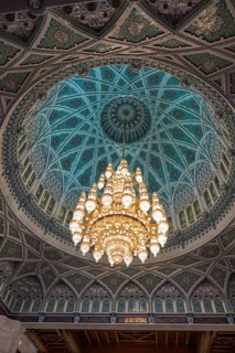 From below a captivating view of the ornately decorated dome and chandelier inside Sultan Qaboos