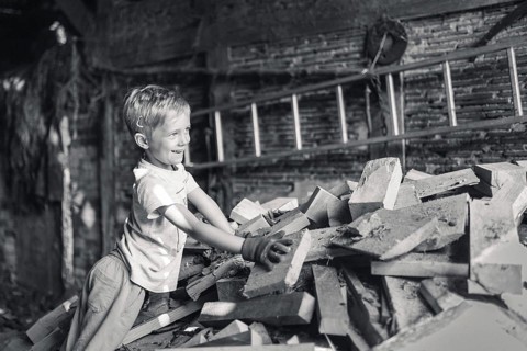 Little boy working in a shed with wood