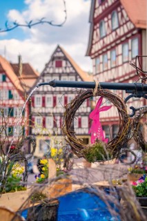 Colourful Easter wreaths with bunny motif in front of half-timbered houses in the background, Calw,