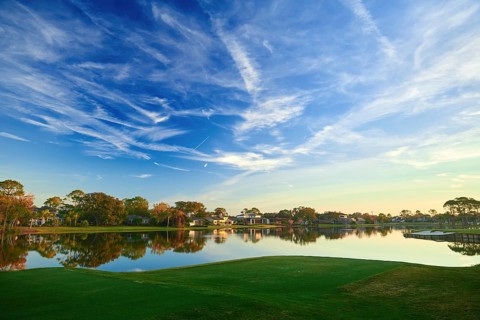 A serene landscape featuring a tranquil lake reflecting a vibrant blue sky and scattered clouds in