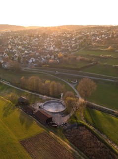 A village surrounded by wide fields and trees at sunset, quiet rural scenery, Gechingen, district
