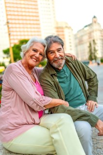 Vertical portrait of a lovely mature couple sitting in an urban bench