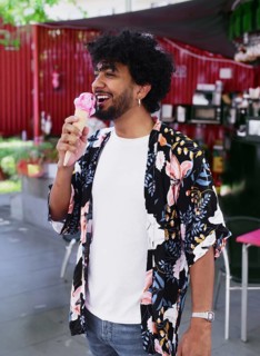 A cheerful man savors a refreshing ice cream cone while enjoying a sunny summer day. Dressed in