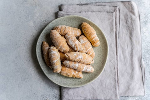 Top view of a plate filled with freshly baked homemade pastries, lightly dusted with flour, set
