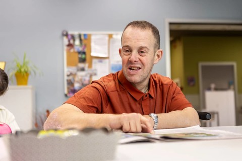 A cheerful man participates in activities at a day center for individuals with intellectual