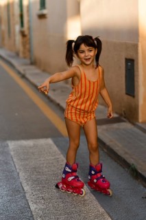 A joyful child roller skating in Santa Maria del Cami, Mallorca, wearing a vibrant outfit. The