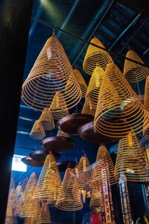 Spiral incense hanging from the ceiling of a dark, atmospheric Taoist and Chinese Buddhist temple