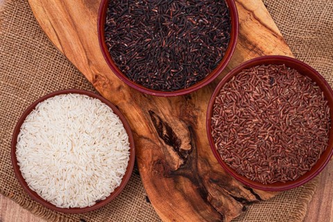 Set of red and black and white rice, in a bowl, on a wooden surface, rustic style, top view