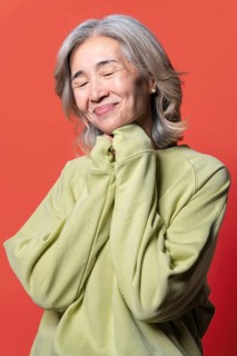 Asian Chinese senior woman with gray hair and a gentle smile, wearing a light green sweater and