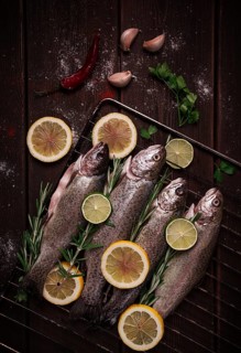 Raw rainbow trout, with lemon and herbs, on a wooden table, no people