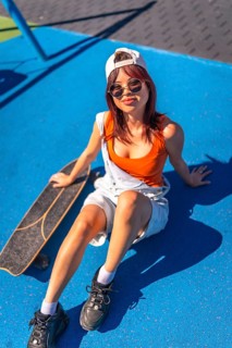 Vertical top view of a chinese young urban woman sitting on colorful skateboard park in the city