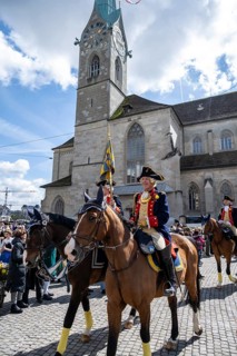 Historically costumed guild members in Zurich's old town, riders in front of the Fraumünster