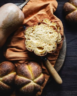 Freshly baked homemade pumpkin bread displayed on a rustic wooden table alongside a butternut