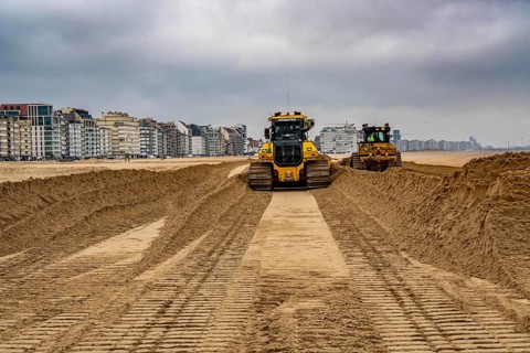Bulldozers when distributing sand on the beach in the town of Knokke-Heist, part of coastal