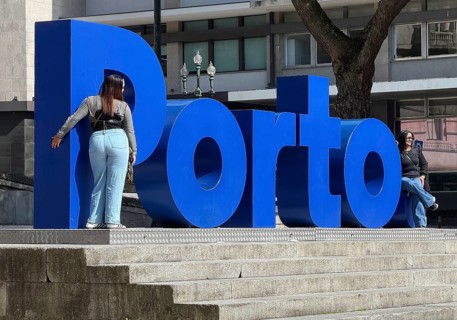 Two woman are photographed in front of the big blue Porto logo at City Hall, Câmara Municipal do