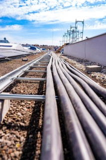 Cables run across a flat gravel roof in sunny weather with blue skies, PV installation. OBI